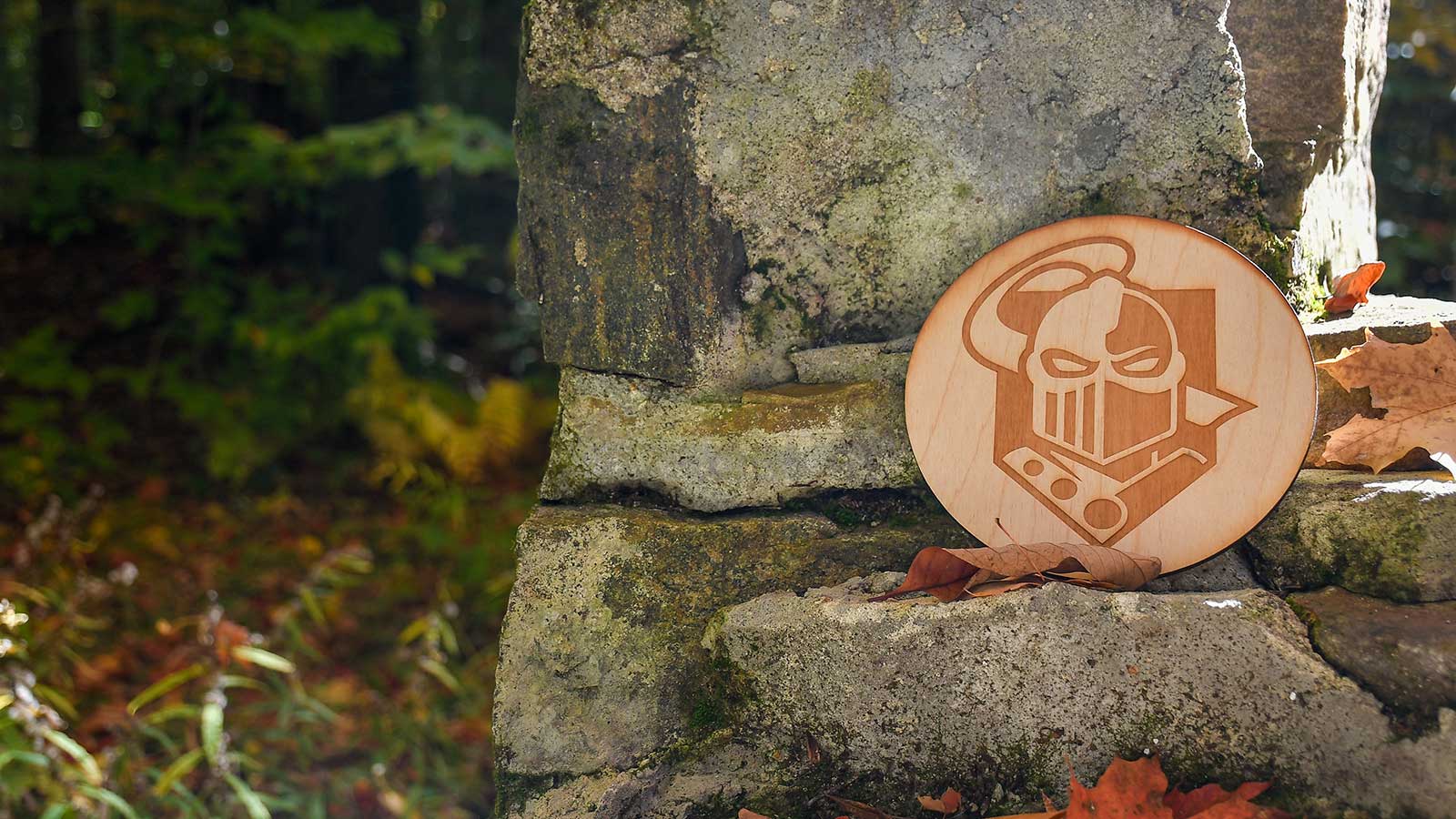 Wooden circle with  Golden Knight logo on it set on natural rocks and plants.